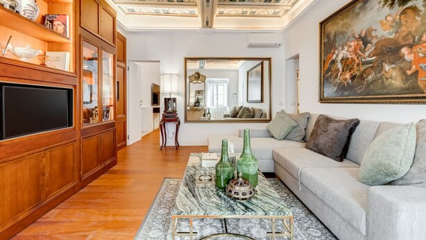 A living room with a wooden bookshelf, a large painting, and a sofa. - Babuino 55 - FromHometoRome (Roma)