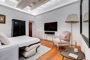 A modern bedroom with a skylight, a bed, a desk, a chair, and a TV.