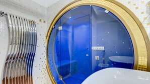 A bathroom with a large circular window, a bathtub, and a shower area. - Babuino 55 - FromHometoRome (Roma)