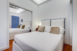 A hotel room with a large bed, a smaller bed, a wardrobe, and a skylight.