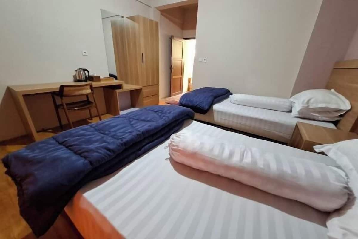 Une chambre avec deux lits, un bureau et une armoire.