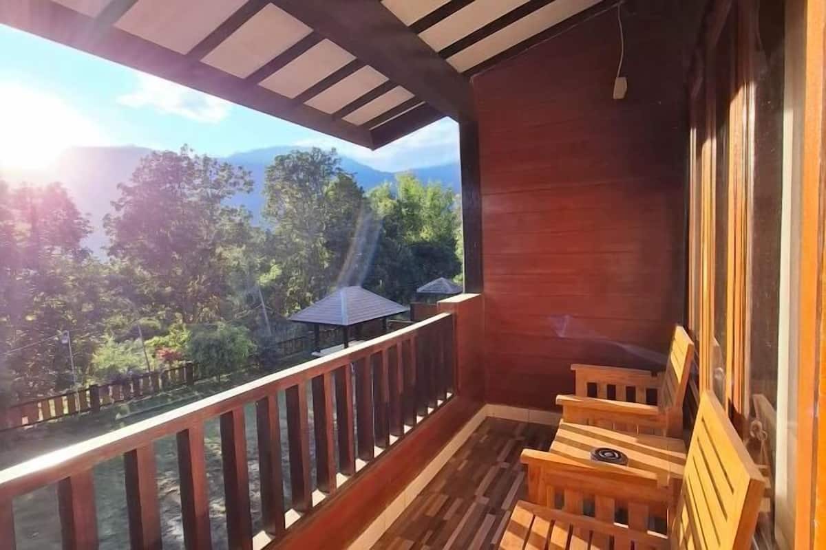 Une terrasse en bois offrant une vue sur les montagnes et les arbres.