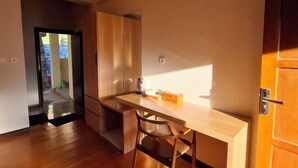 Cocina compacta con encimera de madera, una silla y una puerta que da a un espacio exterior.