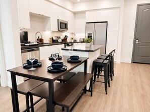 A modern kitchen with white cabinetry, a central island, and a dining area with a dark wooden table and matching chairs.