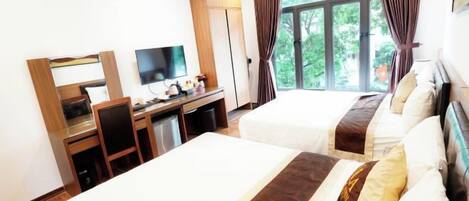 A hotel room with two beds, a desk with a TV, and a window with curtains.