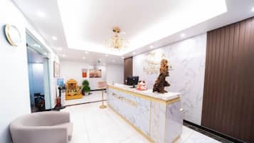 A reception area with a marble counter, a chandelier, and a reception desk.