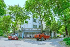 A building with a sign reading 'NHÀ NGHI LAM ANH' and two parked cars in front. - Lam Anh Hotel 1 Phap Van Hoang Mai (Hanoi)