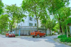 A building with a sign reading 'NHA NGHI LAM ANH' and two parked cars in front. - Lam Anh Hotel 1 Phap Van Hoang Mai (Hanoi)