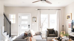 Ein Wohnzimmer mit grauem Sofa, Couchtisch, Gitarre und Fernseher.