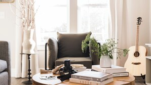 Ein gemütliches Wohnzimmer mit einem braunen Ledersessel, einem Holztisch, einer Gitarre und Büchern.