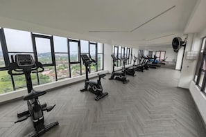 Une salle de sport équipée de matériel d’exercice et dotée de grandes fenêtres offrant une vue dégagée.