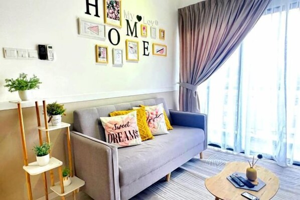 Un salon avec un canapé, une table basse et un mur orné de tableaux et d’une inscription « HOME ».