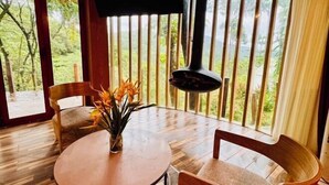 Uma mesa de jantar de madeira com cadeiras, um vaso com flores e uma TV fixada na parede.