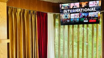 A hotel room with a bed, curtains, and a TV displaying an international channel.