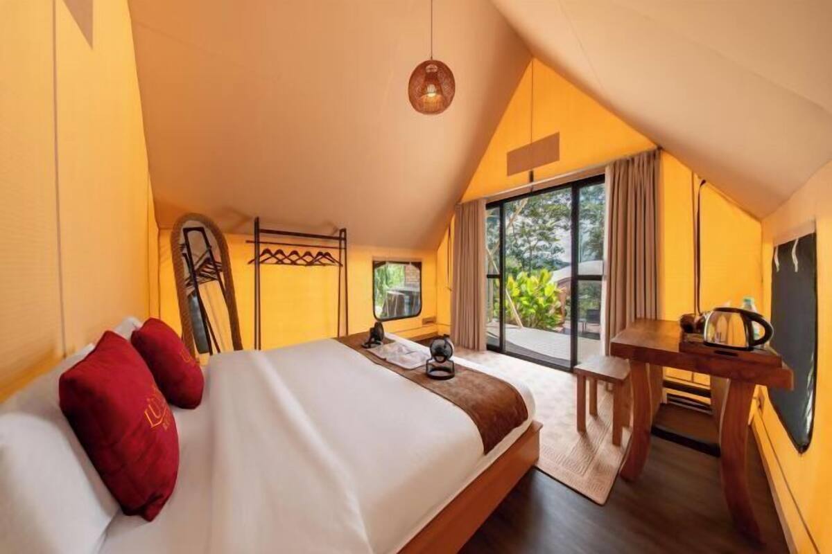 A bedroom with a bed, a desk, and a view of the outdoors.