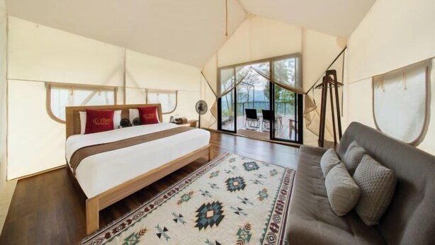 A bedroom with a large bed, a sofa, a patterned rug, and a view through large windows. - Lu Ying Retreats (Bentong)