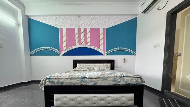 A bedroom with a bed, a decorative wall, and a door. - Sathya Hotels & Resorts (Hyderabad)