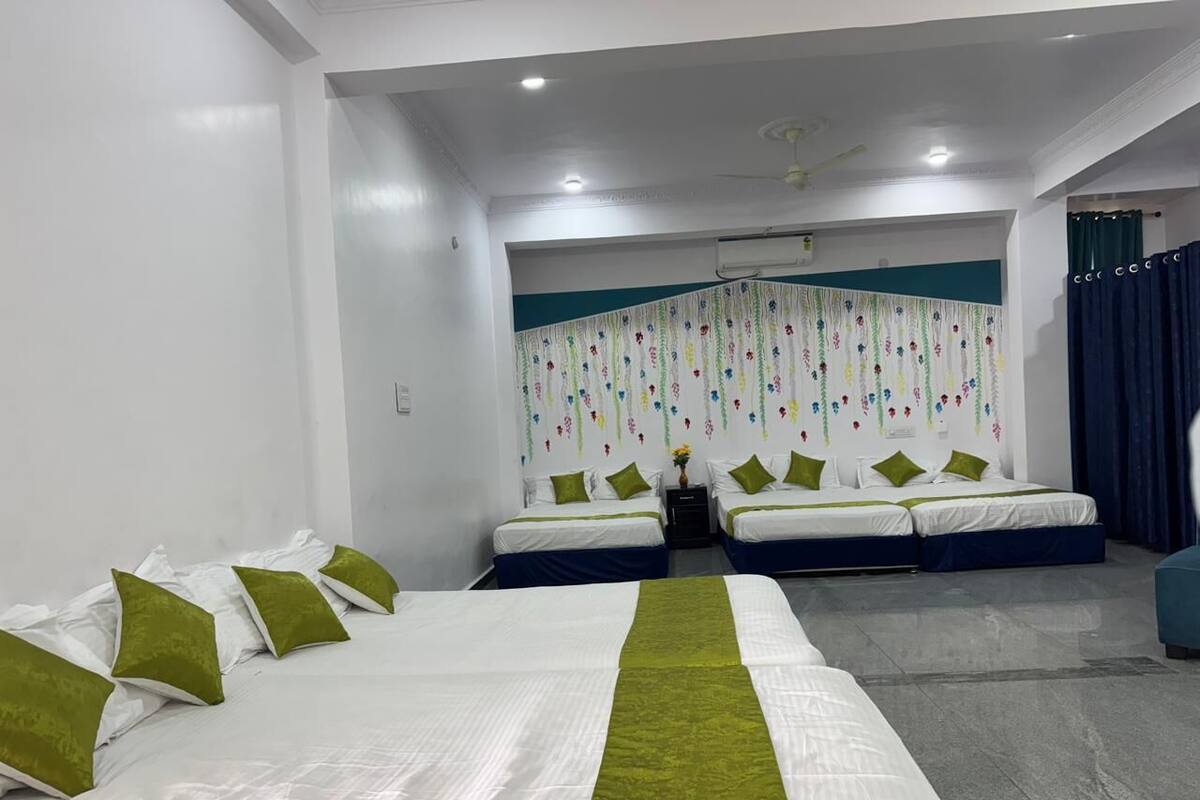 Una habitación de hotel con una cama grande, dos camas más pequeñas y una zona de estar.