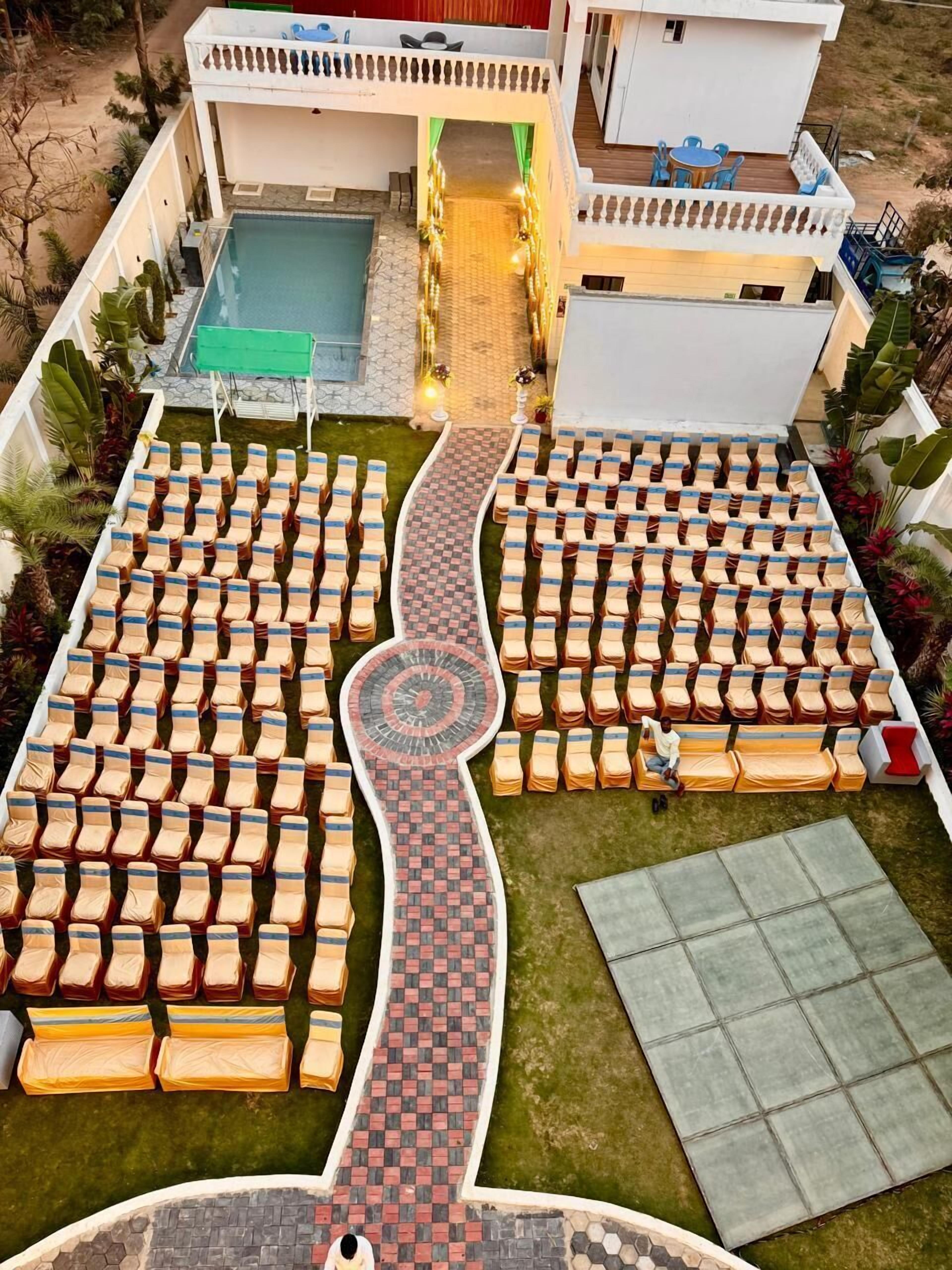 Un hotel con piscina, zonas de estar distribuidas y un paseo central.