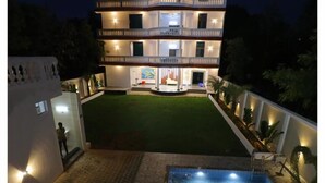 A multi-story building with a swimming pool, a well-maintained lawn, and a white exterior. - Sathya Hotels & Resorts (Hyderabad)