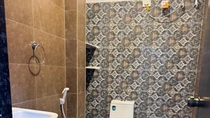 A bathroom with a white toilet, a sink, and a shower. - Sathya Hotels & Resorts (Hyderabad)