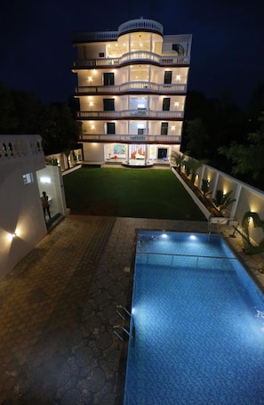 A multi-story building with a swimming pool, a well-maintained lawn, and a white exterior. - Sathya Hotels & Resorts (Hyderabad)
