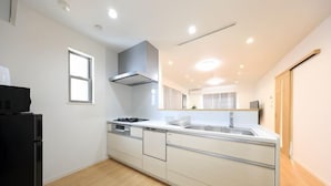 A modern kitchen with white cabinetry, a black refrigerator, a stove, and a sink. - Bliss Ikebukuro (Tokyo)