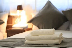 A neatly made bed with a folded white towel and a pillow. - Bliss Ikebukuro (Tokyo)