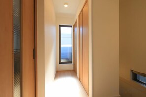 A hallway with a view to a balcony, wooden doors, and a small window. - Bliss Ikebukuro (Tokyo)