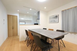 Un comedor moderno con una mesa rectangular, seis sillas y una cocina al fondo.