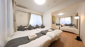 A hotel room with two beds, a ceiling light, a bedside table, and a window with curtains. - Bliss Ikebukuro (Tokyo)