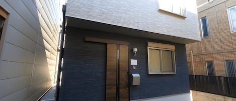 Un edificio moderno de dos pisos con fachada oscura y un ventanal grande.