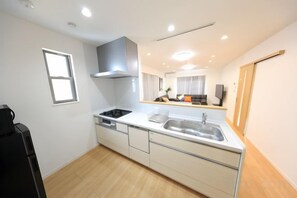 A modern kitchen with a stove, sink, and cabinets. - Bliss Ikebukuro (Tokyo)