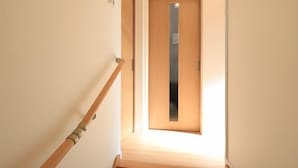A narrow stairway with a wooden handrail leading to a door with a small window. - Bliss Ikebukuro (Tokyo)