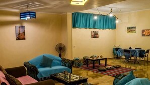 A living room with a sofa, armchair, coffee table, and a dining area with chairs and a table. - Jamila Residential Apartment (Cairo)
