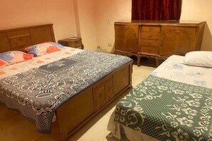Un dormitorio con dos camas, un aparador de madera y una mesita de noche.