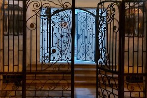 A wrought iron gate with intricate designs, leading to a wooden staircase. - Jamila Residential Apartment (Cairo)