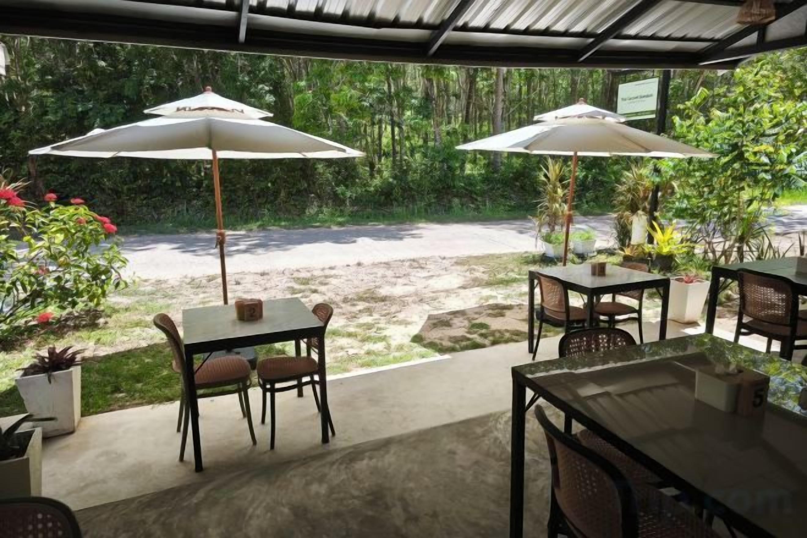 An outdoor patio area with tables and chairs, two umbrellas, and potted plants.