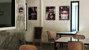 A modern cafe interior with a marble column, wooden chairs, a blackboard menu, and wall art depicting coffee. - The Secret Garden Homestay Koh yao yai (Koh Yao Yai)