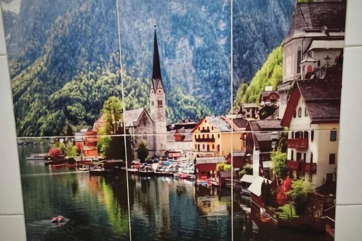 A riverfront town with a prominent church steeple, boats, and traditional buildings.