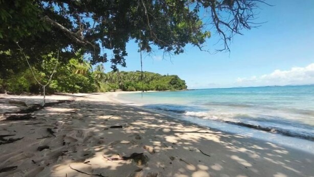 A sandy beach with footprints, a clear blue sky, and a forested area in the background. - The Secret Garden Homestay Koh yao yai (Koh Yao Yai)