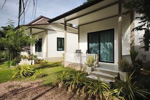 A two-story house with a covered porch, a small garden, and a visible satellite dish. - The Secret Garden Homestay Koh yao yai (Koh Yao Yai)