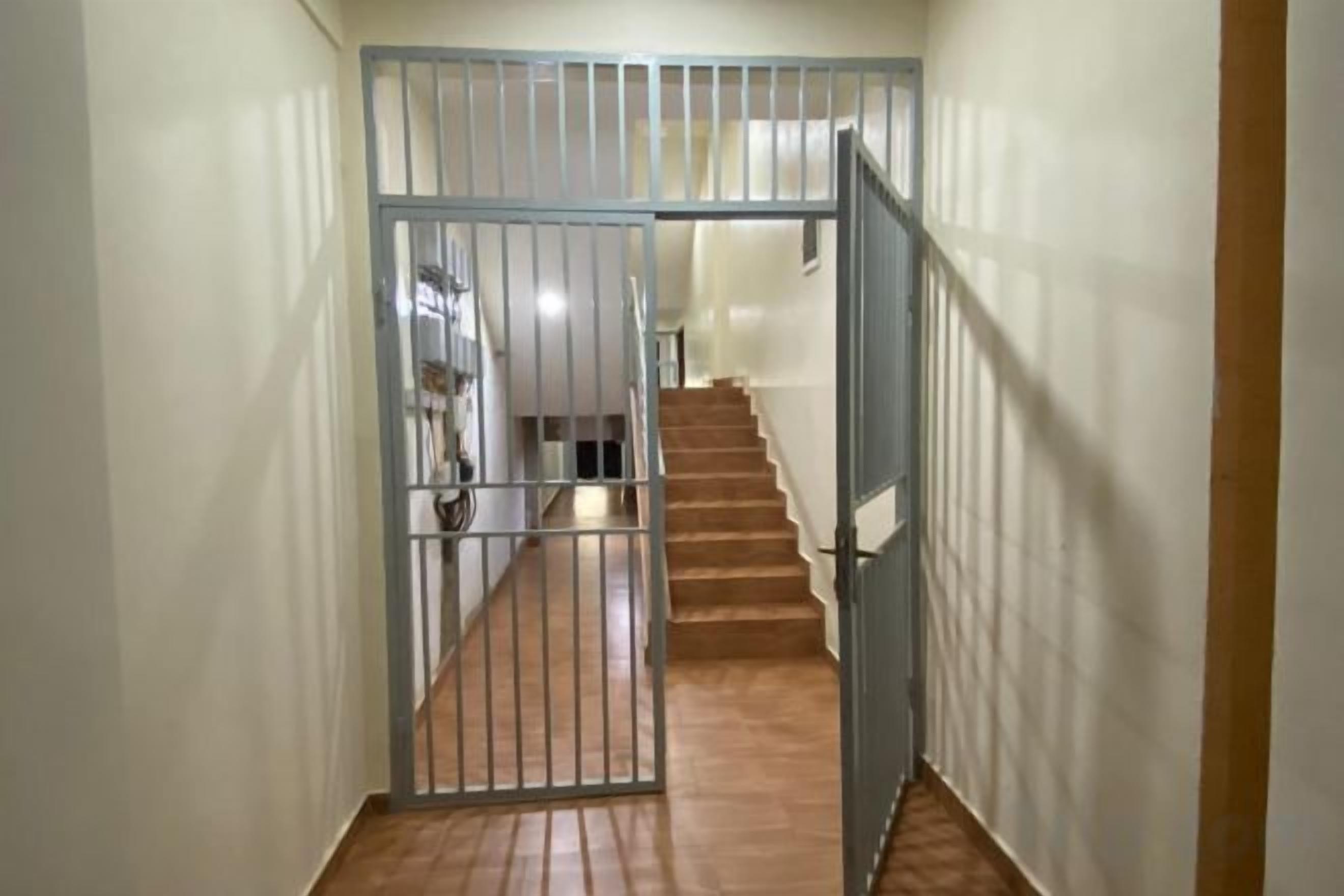 A hallway with a metal gate leading to a staircase.
