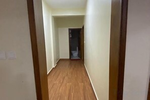 A narrow hallway with wooden flooring and white walls, leading to a room with a toilet visible in the distance. - BIZI HOMES, GIKONDO (Kigali)
