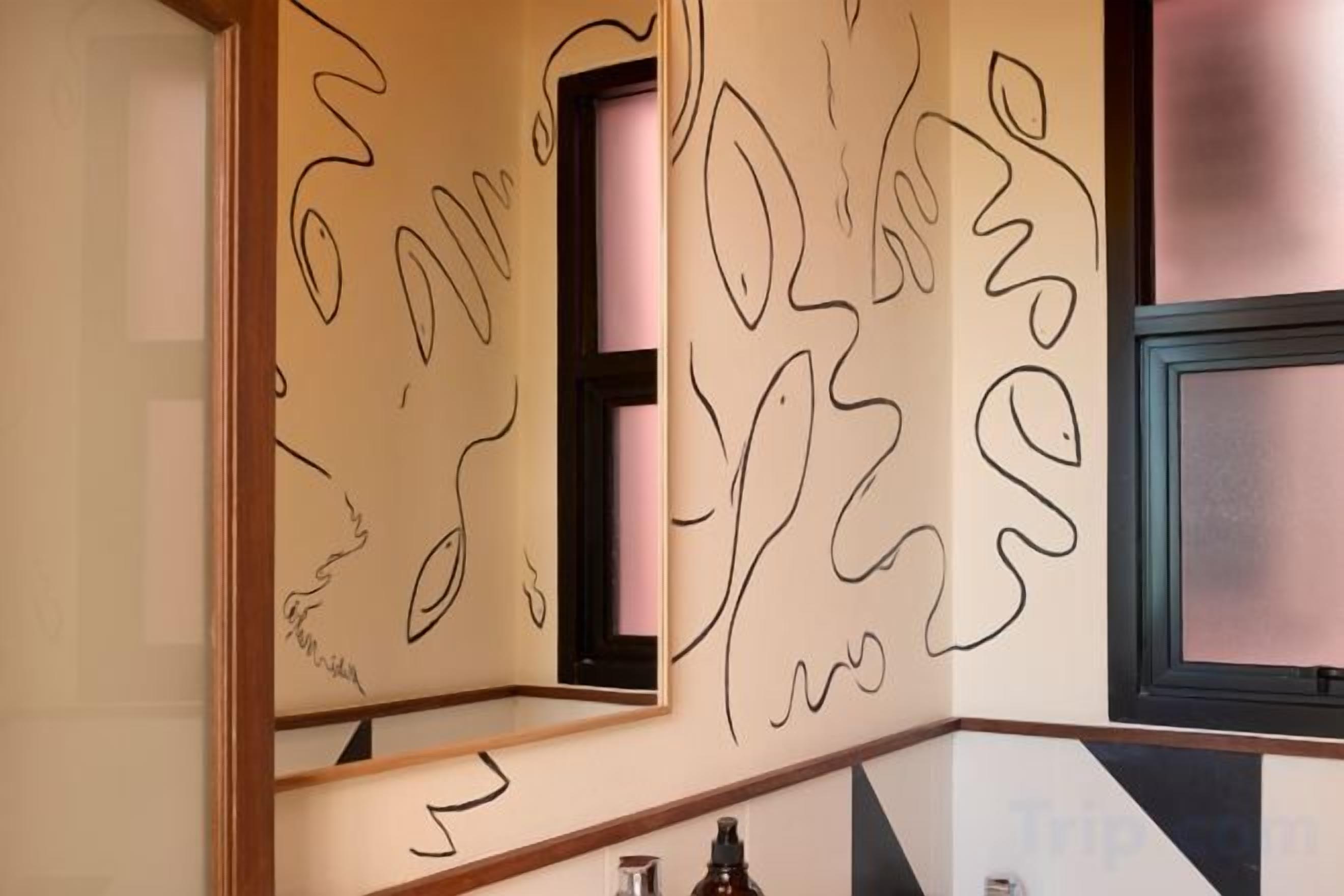 A wall with abstract line art and a window with a black frame.