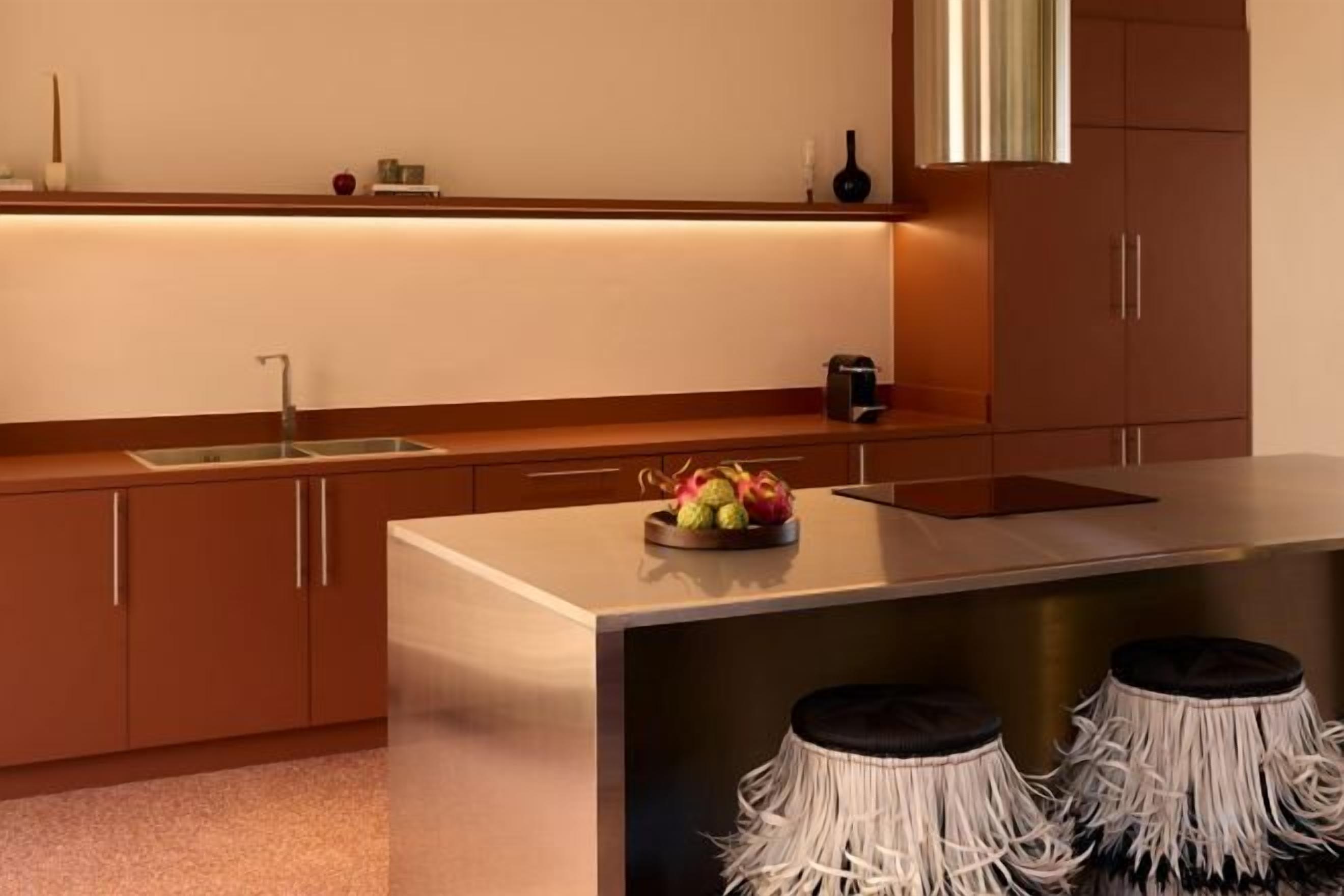 Una cocina moderna con una isla de acero inoxidable, un lavamanos integrado y un frutero.