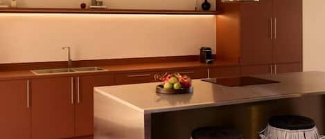 A modern kitchen with a stainless steel island, a built-in sink, and a fruit bowl.