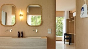 Un baño moderno con tocador de madera, dos espejos montados en la pared y un ventanal con vistas a la vegetación.