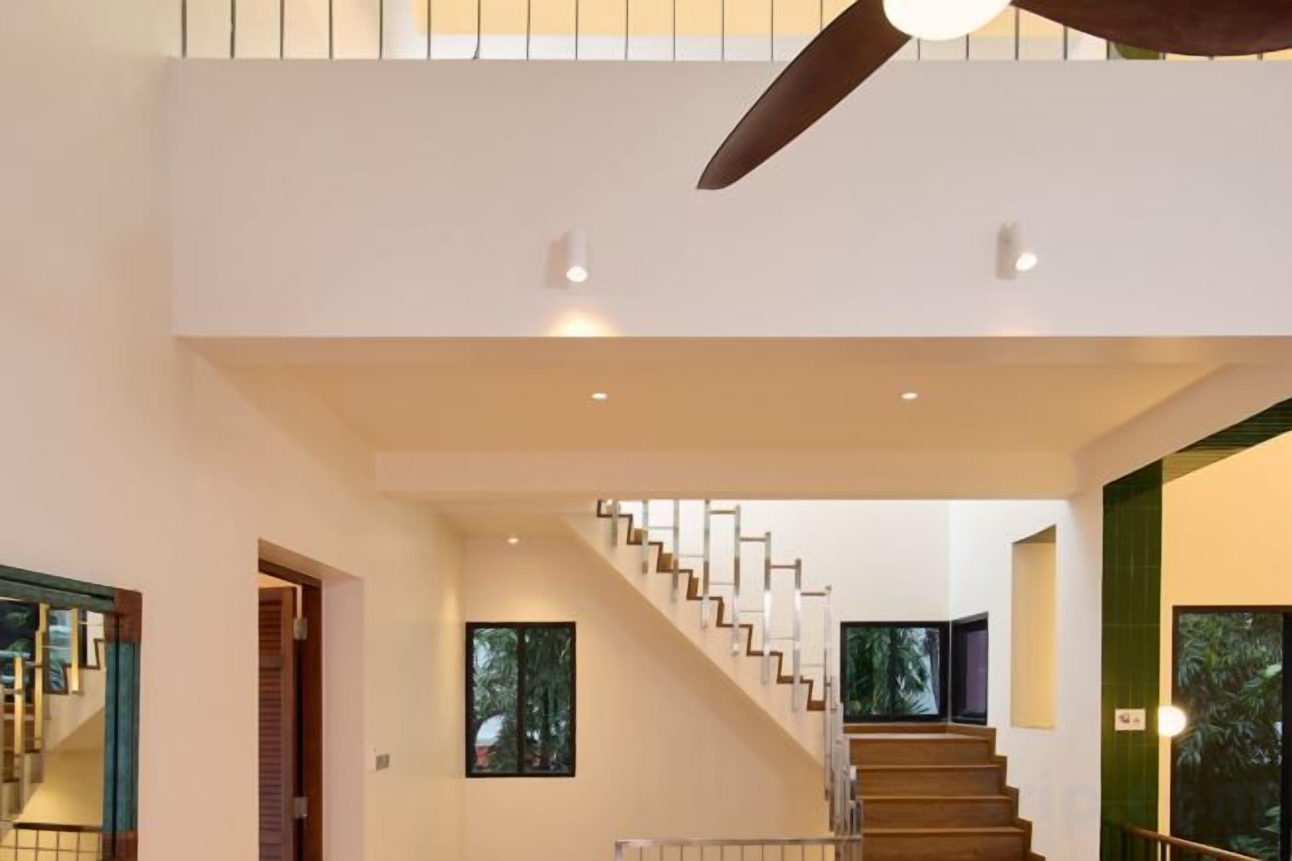 A modern interior with a staircase, a ceiling fan, and recessed lighting.