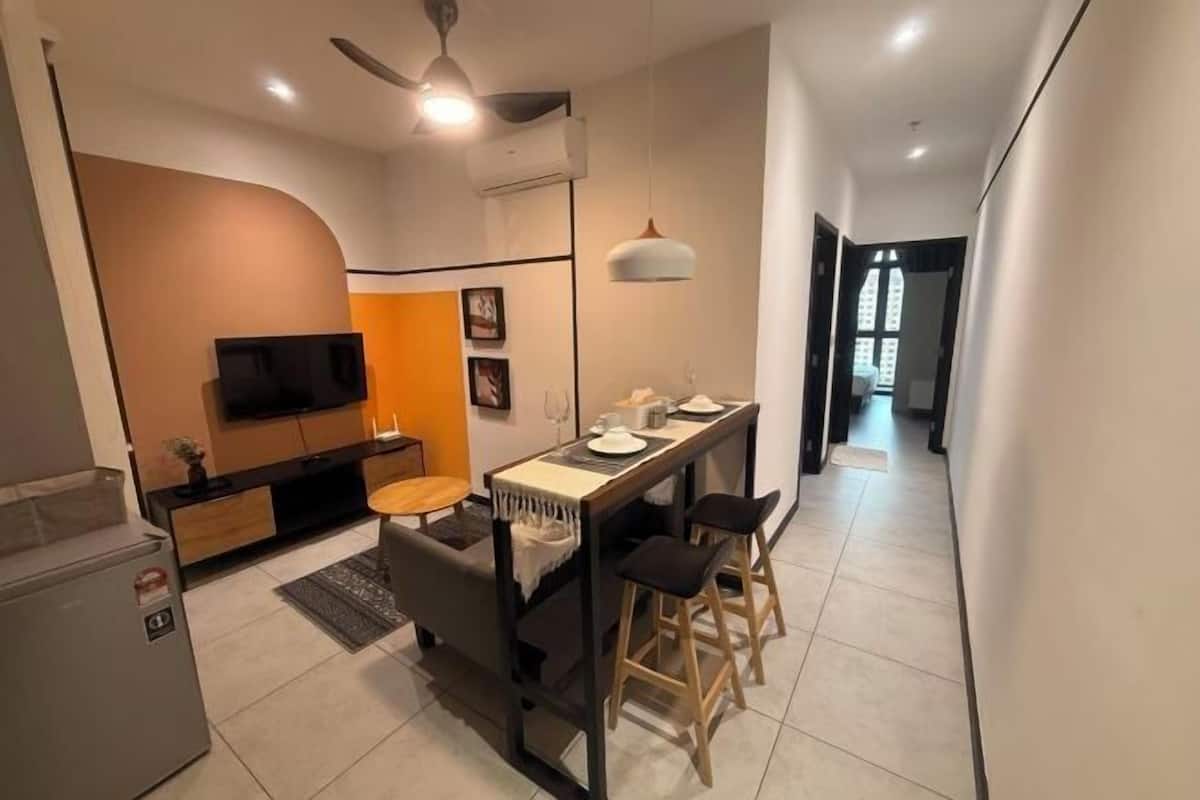 A modern kitchen with a built-in oven, a dining area with a table and chairs, and a TV mounted on the wall.